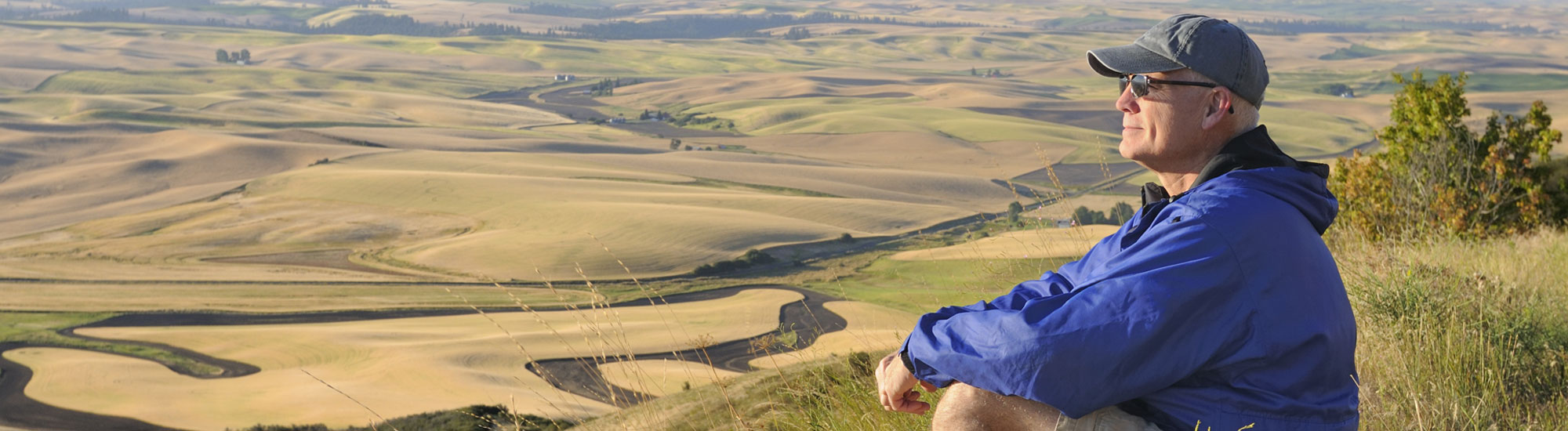senior man staring while sitting on a hill senior man staring while sitting on a hill